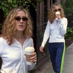 two women walking down the street with cups in their hands and one holding a coffee cup