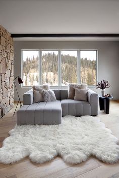 a living room filled with furniture and a large window covered in white fluffy rugs