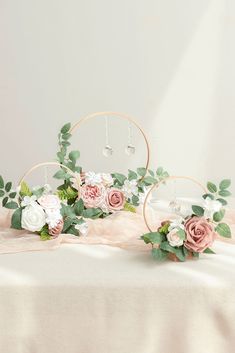 two hoop vases filled with flowers on top of a table