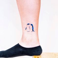 a small penguin tattoo on the leg of a woman's foot, with two penguins painted on it