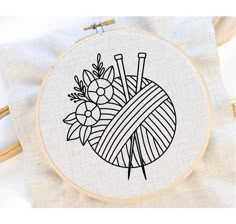 an embroidery project with a ball of yarn and flowers in the center on a white background