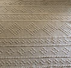 a crocheted blanket is laying on the floor