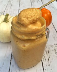 a glass jar filled with peanut butter next to pumpkins