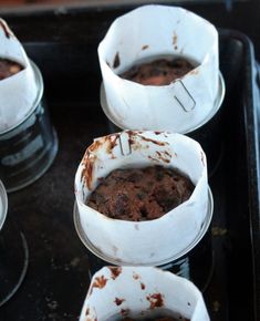 four cups filled with food sitting on top of a black stove burner covered in burnt paper