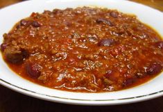 a white bowl filled with chili on top of a wooden table