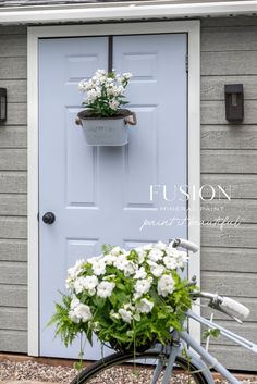 a bicycle parked in front of a blue door with white flowers on the handlebars