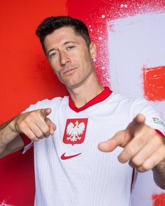 a man pointing at the camera while wearing a red and white soccer jersey with an eagle on it