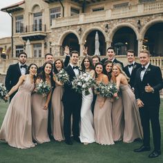 a group of people standing next to each other in front of a building with flowers