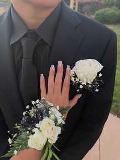 a man in a tuxedo with flowers on his wrist and hands holding the grooms bouquet