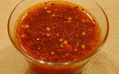 a glass bowl filled with chili sauce on top of a carpeted flooring area