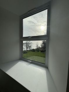 an empty room with the sun shining through the window and grass in the foreground