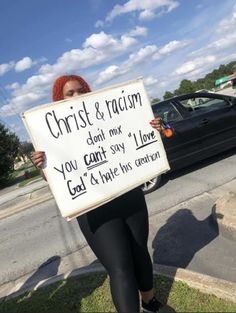 a woman holding a sign that reads christ & racism you can't say i love god and hate his generation