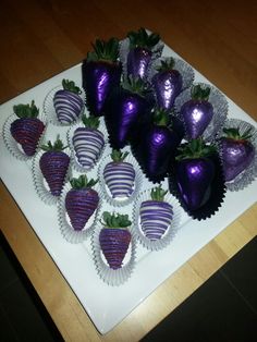 chocolate covered strawberries are arranged on a white platter with purple foil wrappers