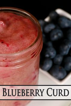 a close up of a jar of fruit on a plate with the words blueberry curd