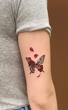 a woman's arm with a butterfly and roses tattoo on the left side of her arm