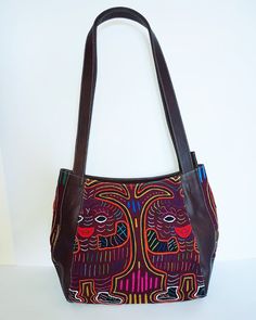 "A brown leather shoulder bag with an exquisite and original hand-sewn Mola decoration on the front.  Each Mola design and textile is 100% unique and 100% handmade by Indigenous Kuna woman. Fashionable, timeless, and practical, a perfect bag for any occasion. Features: - Zippered main compartment for safety - Two inset pockets for mobile/tissues - One interior zippered pocket for money/cards/keys Dimensions: W 27cm x H 23cm x D 10cm - Handle drop 31cm Fabric: Made from high quality leather, dura Embroidered Brown Hobo Tote Bag, Embroidered Brown Tote Hobo Bag, Embroidered Brown Hobo Bag, Brown Leather Hand-stitched Bag, Brown Hand-stitched Leather Bag, Hand-stitched Brown Leather Shoulder Bag, Artisan Brown Leather Hobo Bag, Brown Leather Artisan Hobo Bag, Embroidered Brown Hobo Shoulder Bag