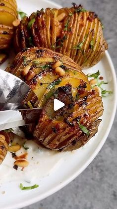 a white plate topped with sliced potatoes on top of a table next to a knife