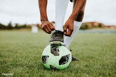 a soccer player tying his shoe on the ball