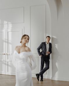 a man in a suit standing next to a woman in a white dress