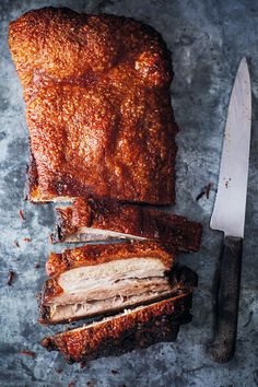 sliced meat sitting on top of a table next to a knife