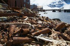 an old rusty boat sitting on top of a pile of rubble next to the ocean