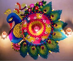 an artisticly decorated peacock is hanging from the ceiling with candles in front of it