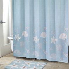 a blue shower curtain with shells and starfishs on it next to a bathtub