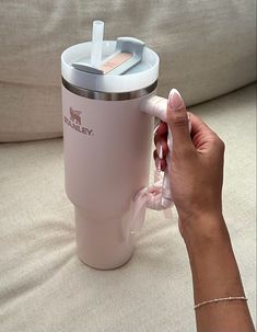 a woman is holding a pink cup with a straw in it and the lid open