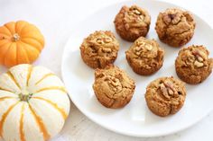 a white plate topped with muffins next to mini pumpkins