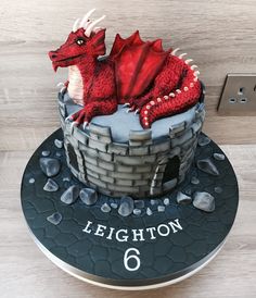 a birthday cake with a red dragon sitting on top of it