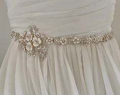 "Unique and romantic.  This enamel floral bridal wedding sash is accented with tons of sparkling crystals. This Delicate wedding belt beautifully compliments  your Boho, rustic or woodland wedding look.  READY TO SHIP  DETAILS * Design measures aprox. 2.25' wide (at widest part by 14\" long. * Offered in silve Metal or or Gold Metal *  Attached at ends to imported French satin ribbon in choice of colors View my complete collection including Bridal Sashes, Bridal Headpieces, Fascinators, Cuff Bra Elegant Cream Sash For Wedding, Elegant Cream Wedding Sash, Elegant Cream Sashes For Wedding, Elegant White Sashes For Ceremony, Elegant White Ceremony Sashes, Elegant Bridal Belt With Flower Decoration For Wedding, White Embellished Sashes For Wedding, Elegant White Bride Sashes, Elegant Bridal Belt With Flower Decoration