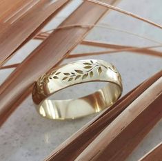 a gold wedding band with leaves on it