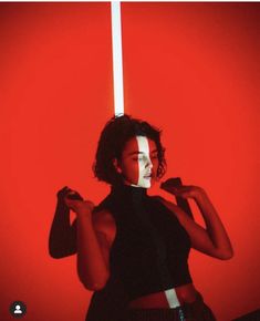 a woman standing in front of a red wall with black and white stripes on her face