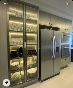 a stainless steel refrigerator in a kitchen with glass doors and shelves filled with plates, bowls and glasses