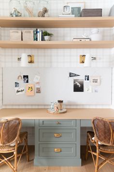 two wicker chairs sit in front of a desk with drawers and pictures on the wall