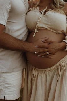 a man and woman are standing next to each other while holding their bellys together