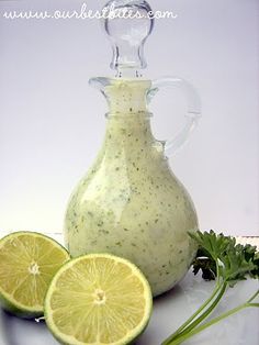 a glass pitcher filled with dressing next to sliced limes