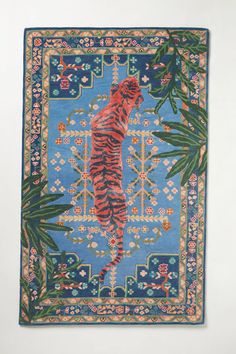 a blue rug with a tiger on it's back and green leaves in the background