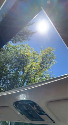 the sun shines brightly through the windshield of a car with trees in the background