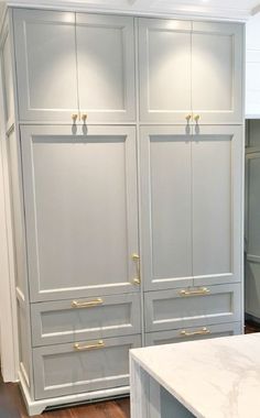 a kitchen with white cabinets and marble counter tops