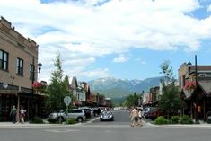 two people are walking down the street in front of some buildings with mountains in the background