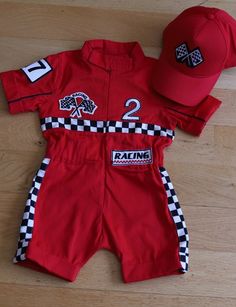 a red baseball uniform and hat laying on top of a wooden floor next to a pair of scissors