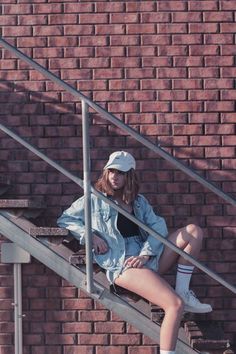 a young woman sitting on the steps in front of a brick wall