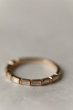 a gold ring with three baguets on it, sitting on a white surface