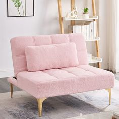 a pink futon couch sitting on top of a rug in front of a window