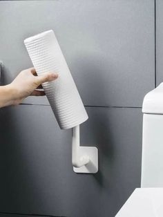 a person holding a toilet paper roll in front of a dispenser on the wall