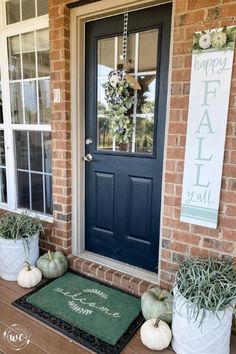 front porch decorated for fall with white pumpkins and greenery on the door mat