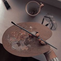 a person is painting on a table with paintbrushes