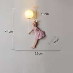 a wall mounted light with a woman in pink dress hanging from it's side