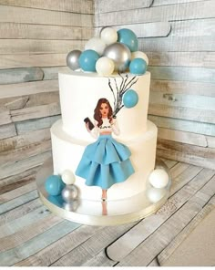 a white cake with blue and silver decorations on it, featuring a woman holding a cell phone